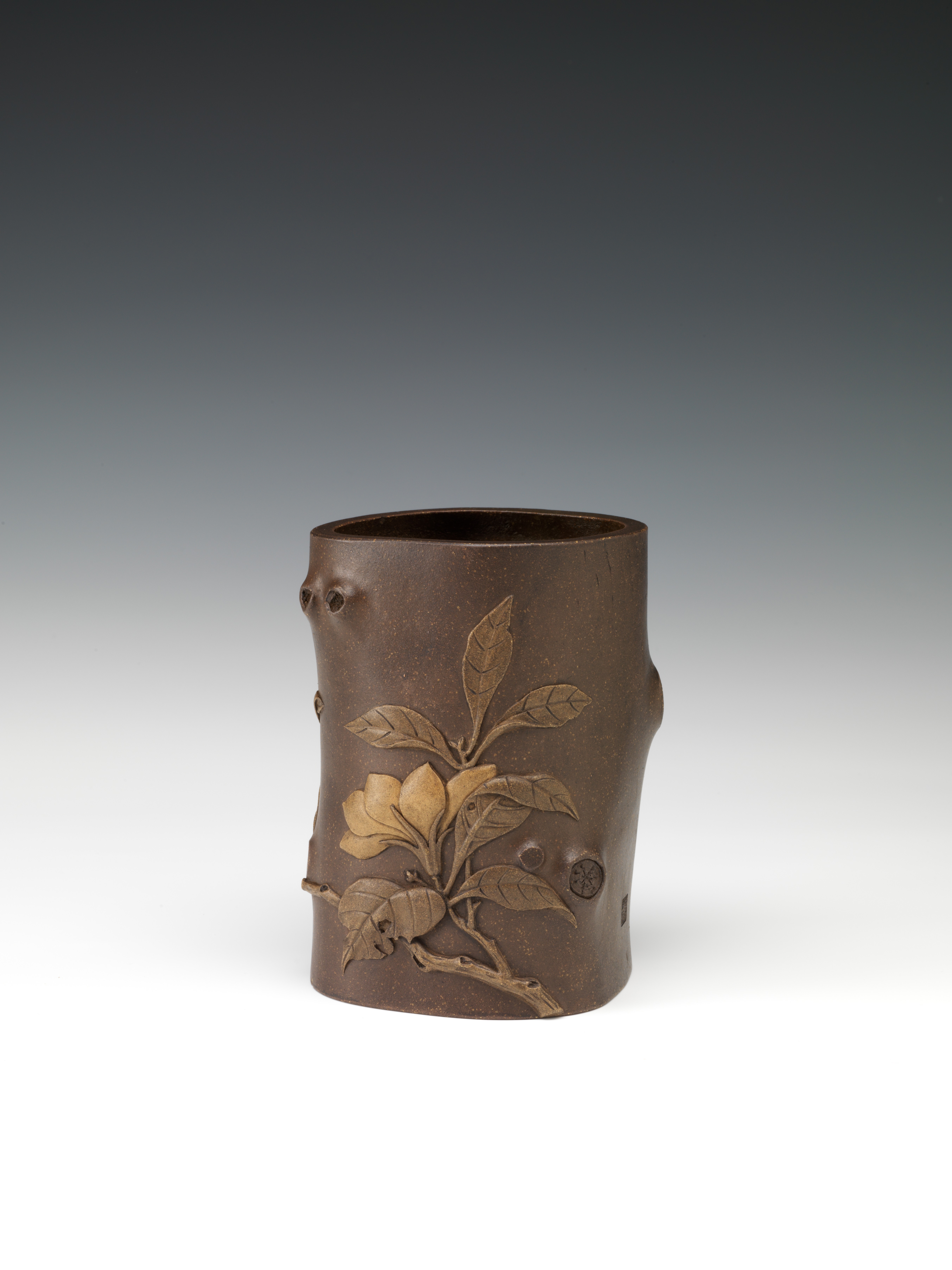 Brush pot in tree trunk form decorated with gardenia branch in relief