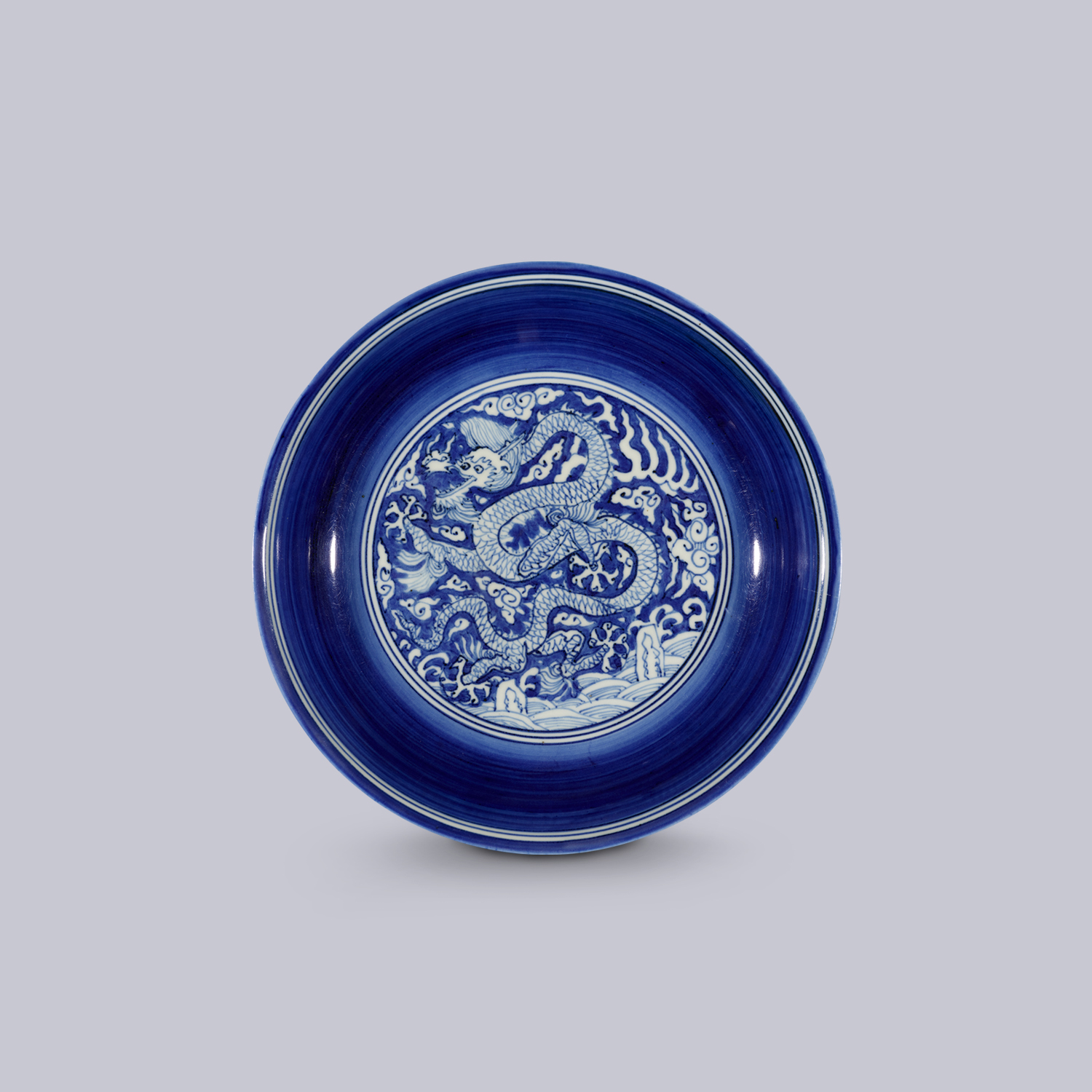 Dish with dragon amidst clouds and waves design on blue ground